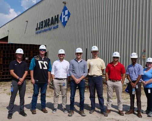 Group wearing 澳门足彩app hardhats gather outside 澳门足彩app Steel facility.